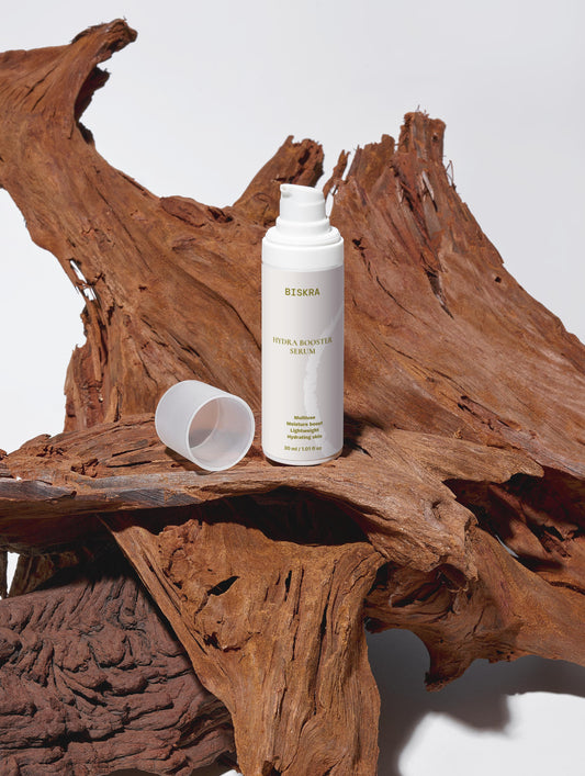 Bottle of Hydra Face Serum with natural ingredients in the background