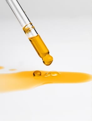 Dropper applying Hydra Booster oil to radiant, glowing skin