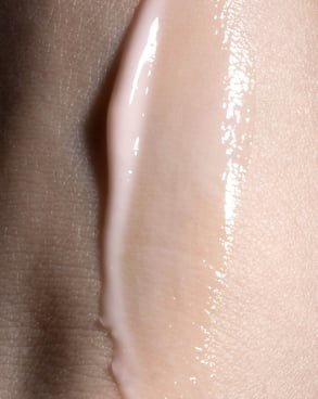 Dropper dispensing serum onto a glowing hand